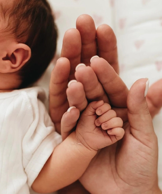 عکاسی نوزاد بدون چهره با دست پدر و مادر